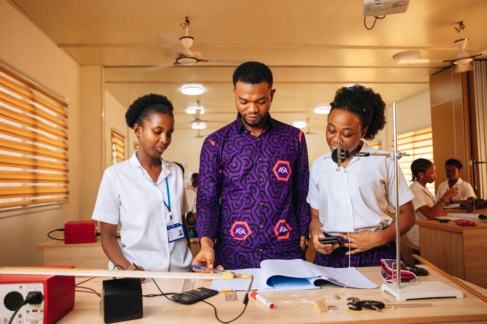 Three ASA students sharing a laptop by their robot village project