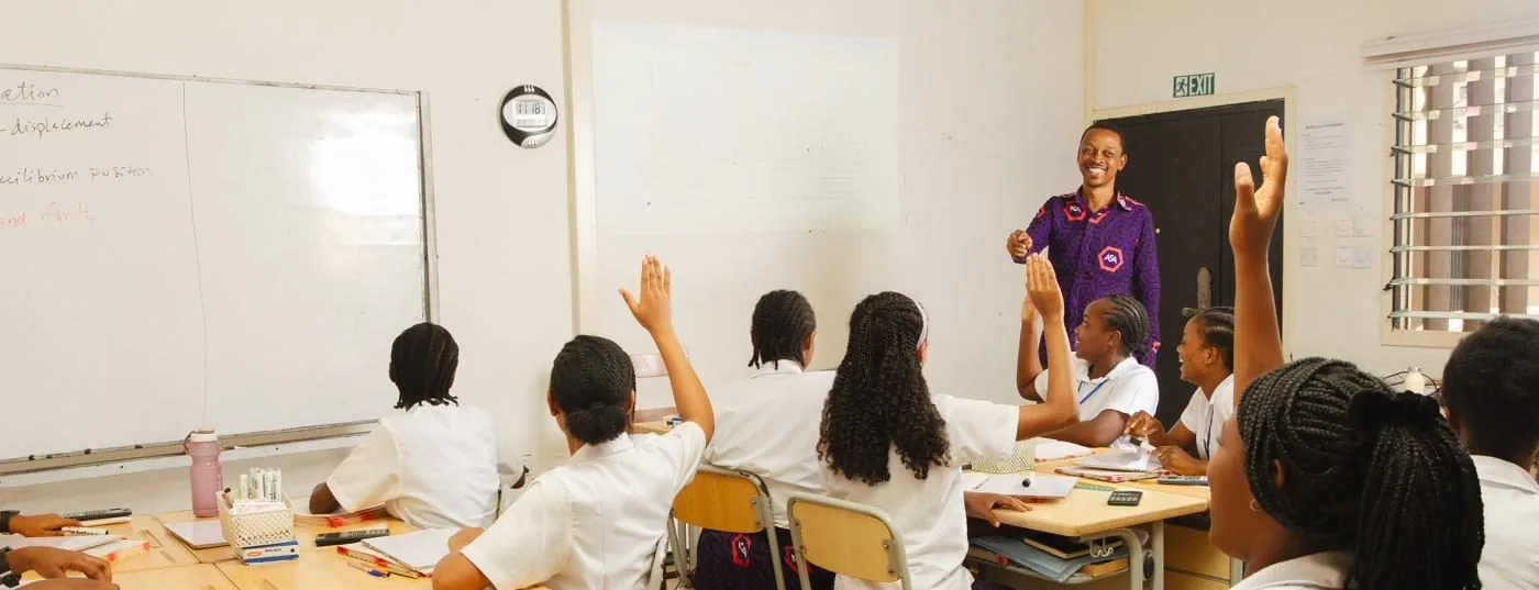 A teacher explaining a mechanics problem at the whiteboard